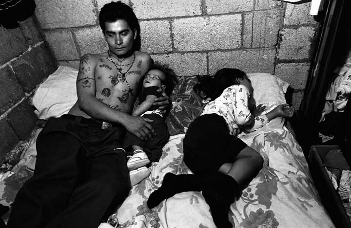 A gang member with his children.  With tattoos it is difficult to find work. Copyright © Donna DeCesare, 2001 Un pandillero con tus hijos.  Con tatuajes no puede conseguir trabajo. Copyright © Donna DeCesare, 2001